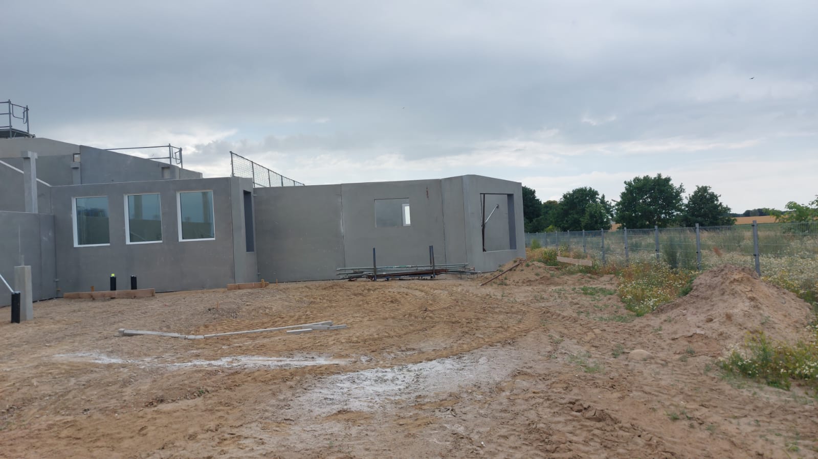 Stallgebäude in Betonfertigteilbauweise mit Fensterreihe unter bewölktem Himmel